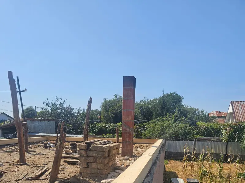 Grindă de lemn nouă, prinsă pe coama unui zid de cărămidă
