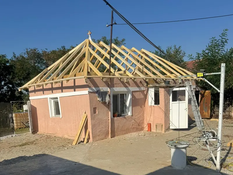 Casă roz cu o șarpantă nouă de lemn în patru ape