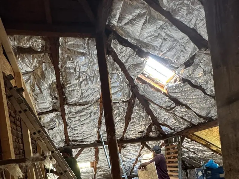 Pod cu izolația cu folie de aluminiu între căpriori și o fereastră de mansardă