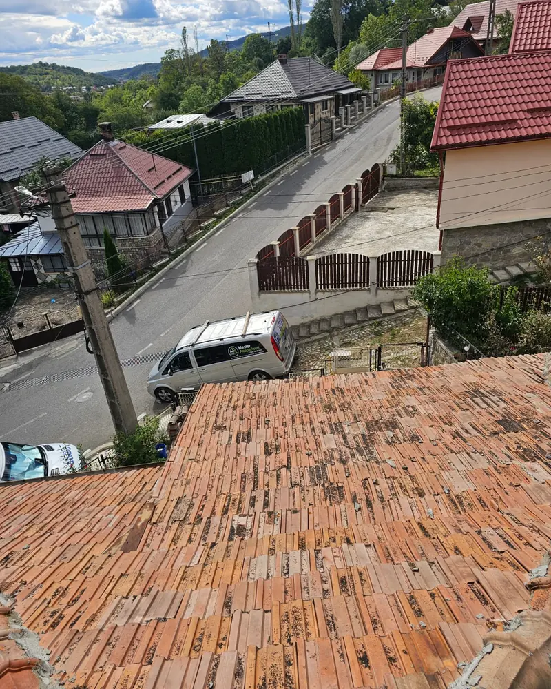 Acoperiș vechi din țiglă ceramică, văzut de sus, deasupra unei străzi