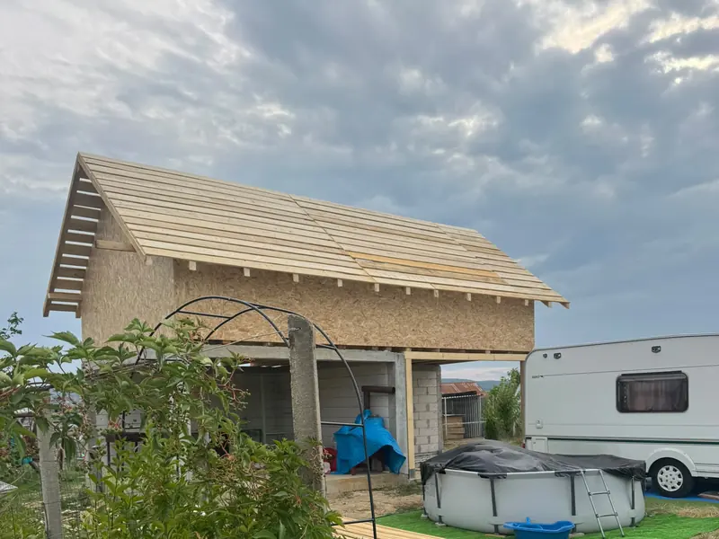 Construcție din lemn cu acoperiș în două ape și astereala bătută, într-o grădină