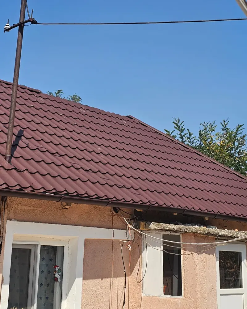 Acoperiș în patru ape din țiglă metalică vișinie, cu jgheabul montat